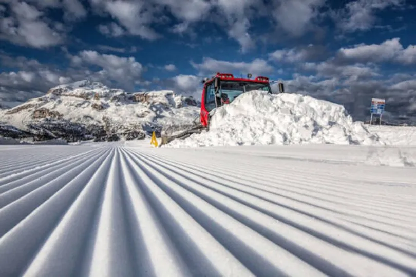 pristine corduroy grooming the focus of the shot, with the red snowcat visible pushing a huge pile
