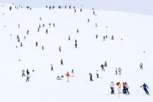 Colourful skiers dotted over a white piste