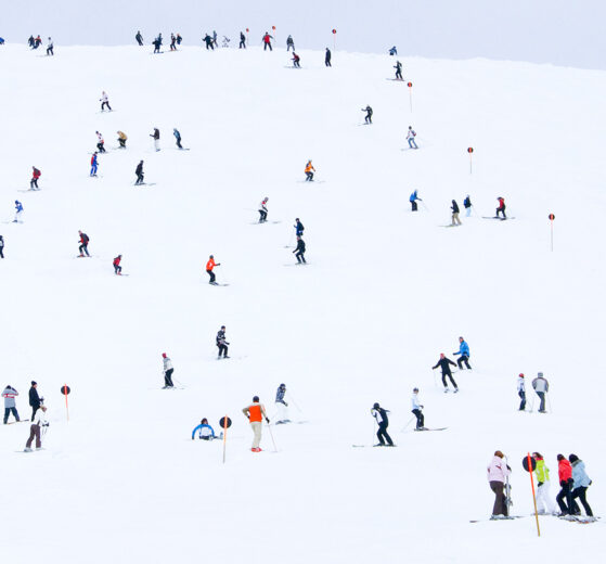Colourful skiers dotted over a white piste
