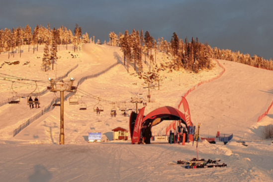 an orange glow casts light over a ski resort, with a chairlift ferrying skiers by two uphill