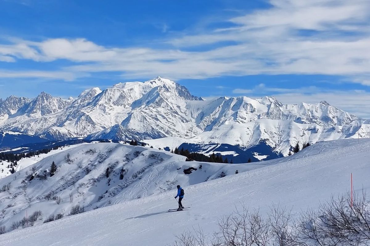 Skier cruising below Mont Blanc on a bluebird day in La Giettaz