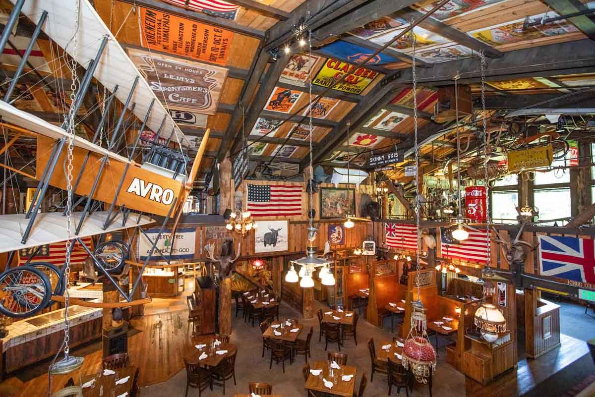 an eclecticly decorated wooden bar, with a mezzanine layer and all sorts hanging from the roof is shot, empty, but looks to be a great place to eat and drink. It's American saloon style