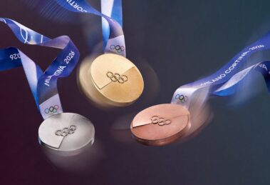 A dynamic image of the Olympic medals in motion, their textures catching the light. The iconic Milano Cortina 2026 ribbon swirls through the air, adding a sense of celebration and movement to the medal design.