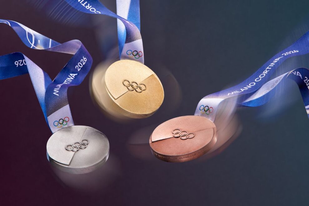 A dynamic image of the Olympic medals in motion, their textures catching the light. The iconic Milano Cortina 2026 ribbon swirls through the air, adding a sense of celebration and movement to the medal design.