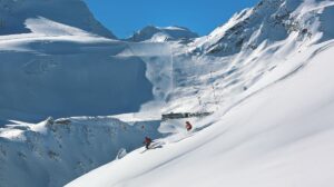Skiers descending near Rettenbach glacier with lift infrastructure in background
