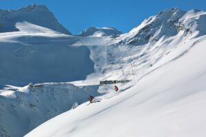 Skiers descending near Rettenbach glacier with lift infrastructure in background