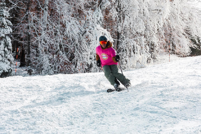 a skier in a pink t shirt makes turns on chopped up snow
