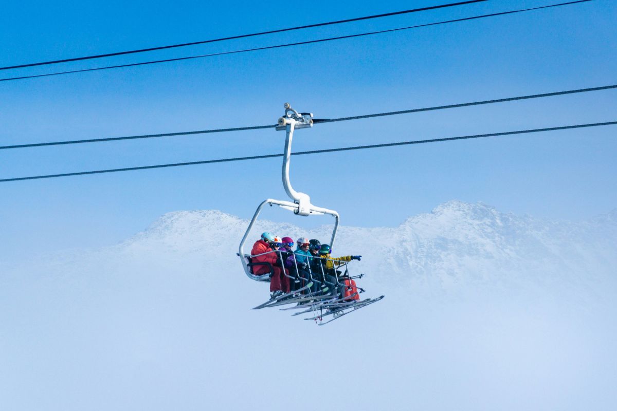 Skiers on a chairlift in the Alps under blue sky