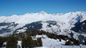 Skiers on a sunny piste in Les Arcs with panoramic views over Villaroger
