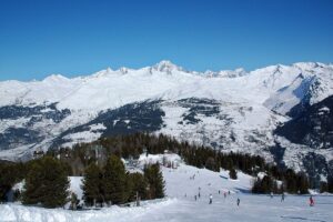 Skiers on a sunny piste in Les Arcs with panoramic views over Villaroger