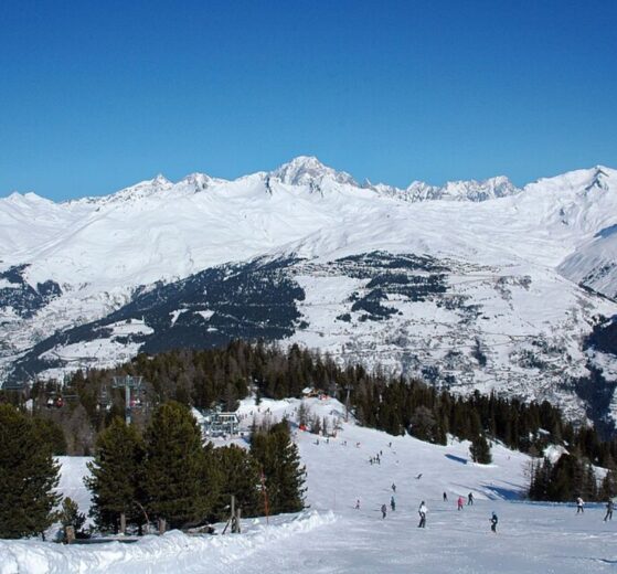 Skiers on a sunny piste in Les Arcs with panoramic views over Villaroger