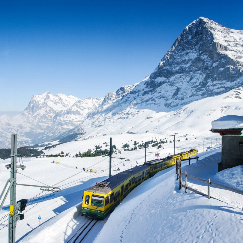 a yellow train under the north face of the Eiger