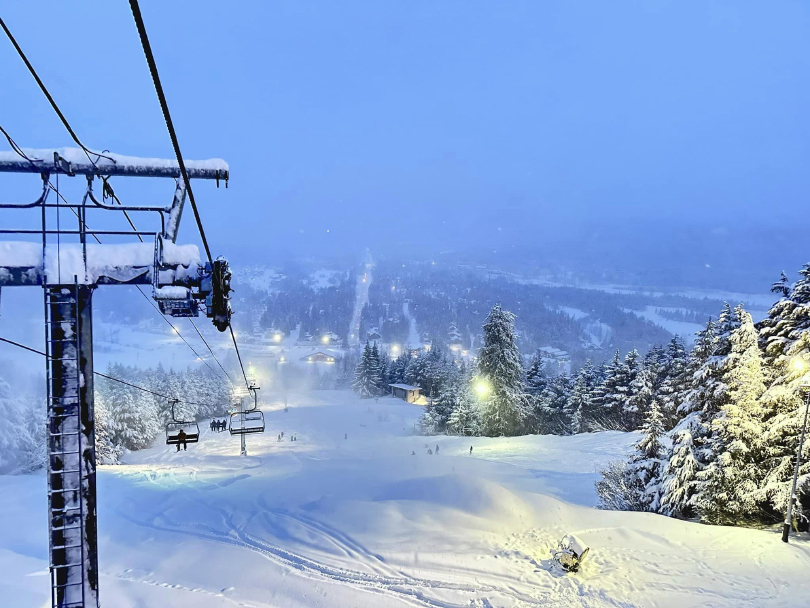 a chairlift under snow, with people on the chairlift, though it's seemingly shot at dusk