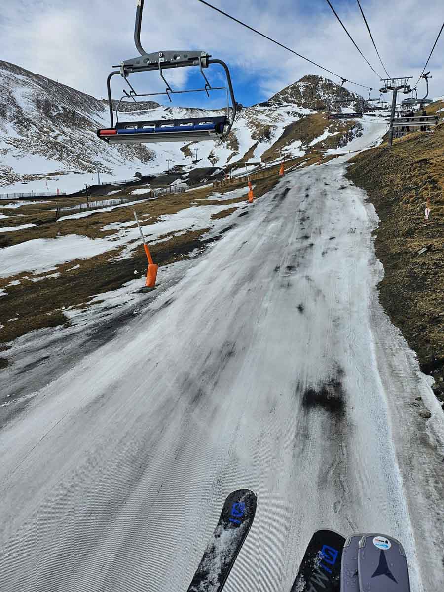 a ribbon of dirty piste through brown fields under a chairlift
