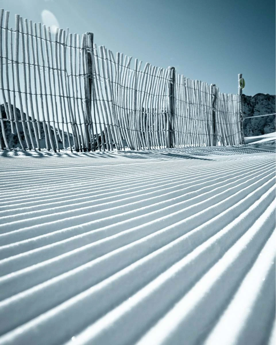 perfectly groomed piste corduroy, with a frosty fence behind