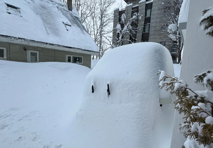 a tiny car covered in snow, just the wipers visible