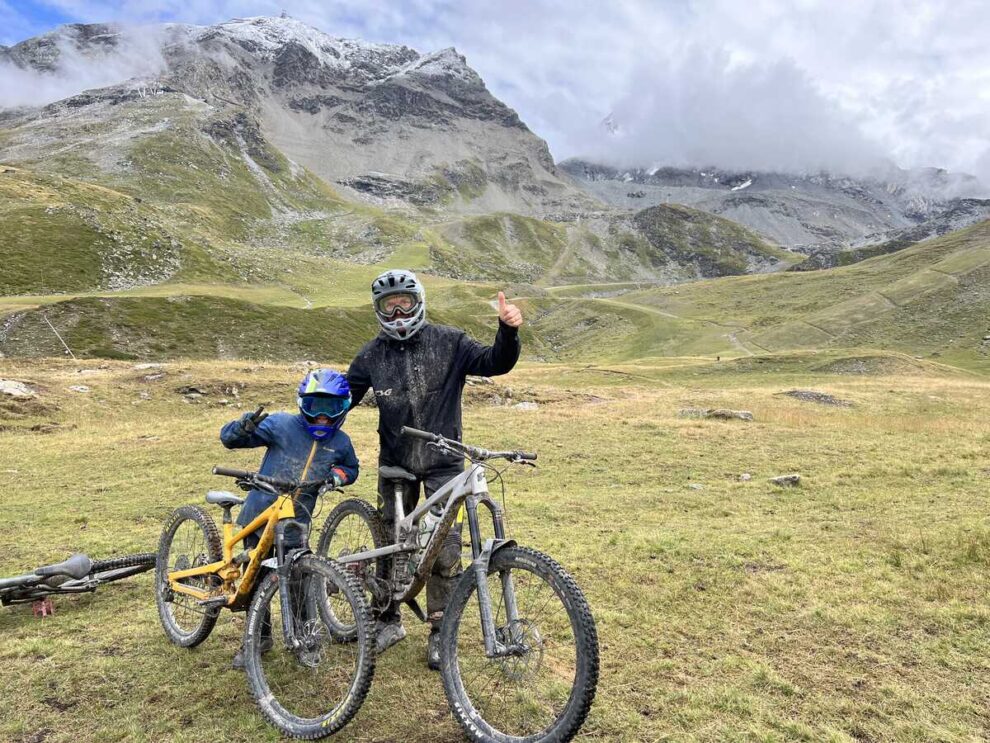 father and son by bikes in the green mountains, decked out for mountain biking