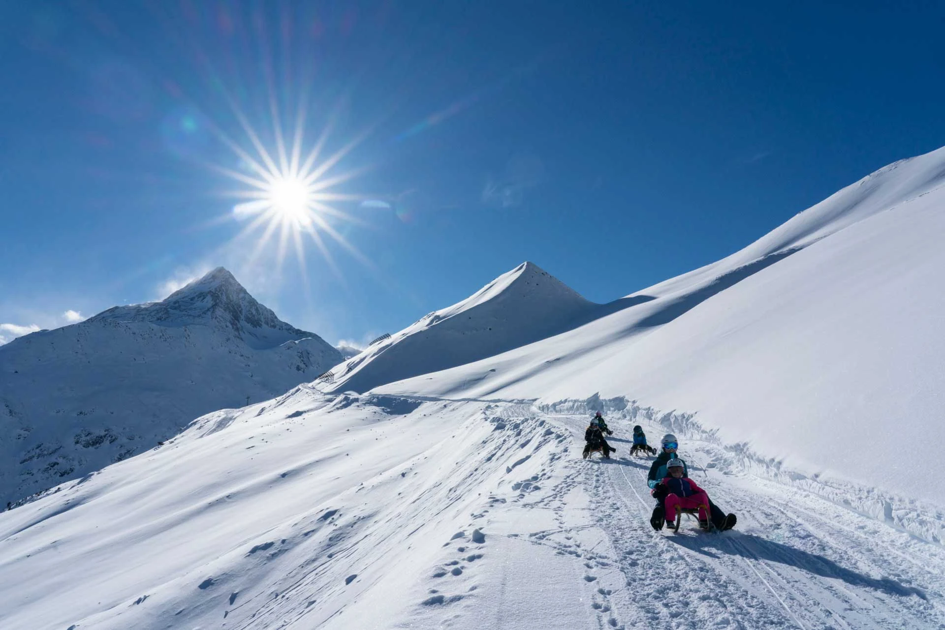 a family of sledders on a cat track under the sun