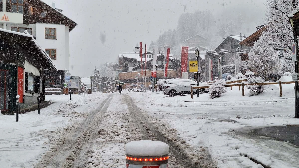 a snowy ski village street, with fresh heavy snow turning to slush on the road