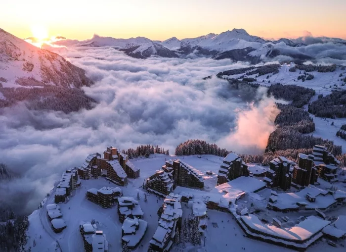 The architecturally significant village of Avoriaz, pictured from above, above the clouds at the top of the mountain with high peaks for company (at sunset)