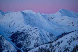 a pink end of a sunset over a vast, white-covered mountain range