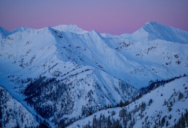 a pink end of a sunset over a vast, white-covered mountain range