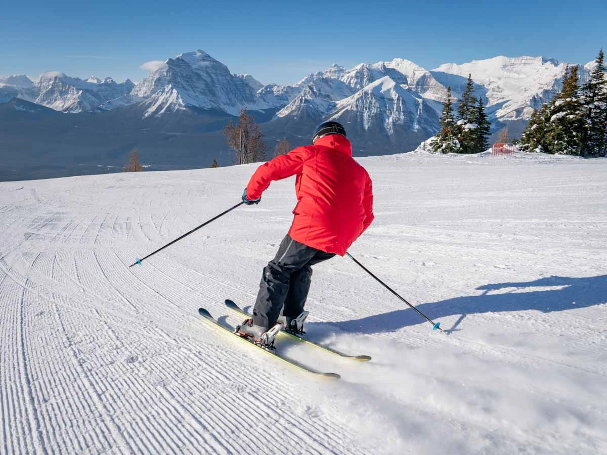 skier in red skis away from camera on fresh piste