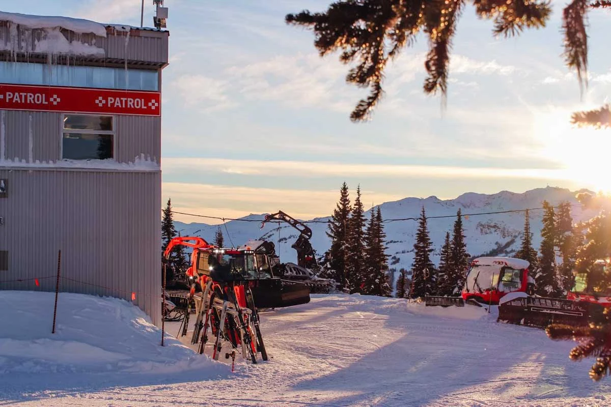 a mountain sunset by a mountain station where red piste bashers are parked