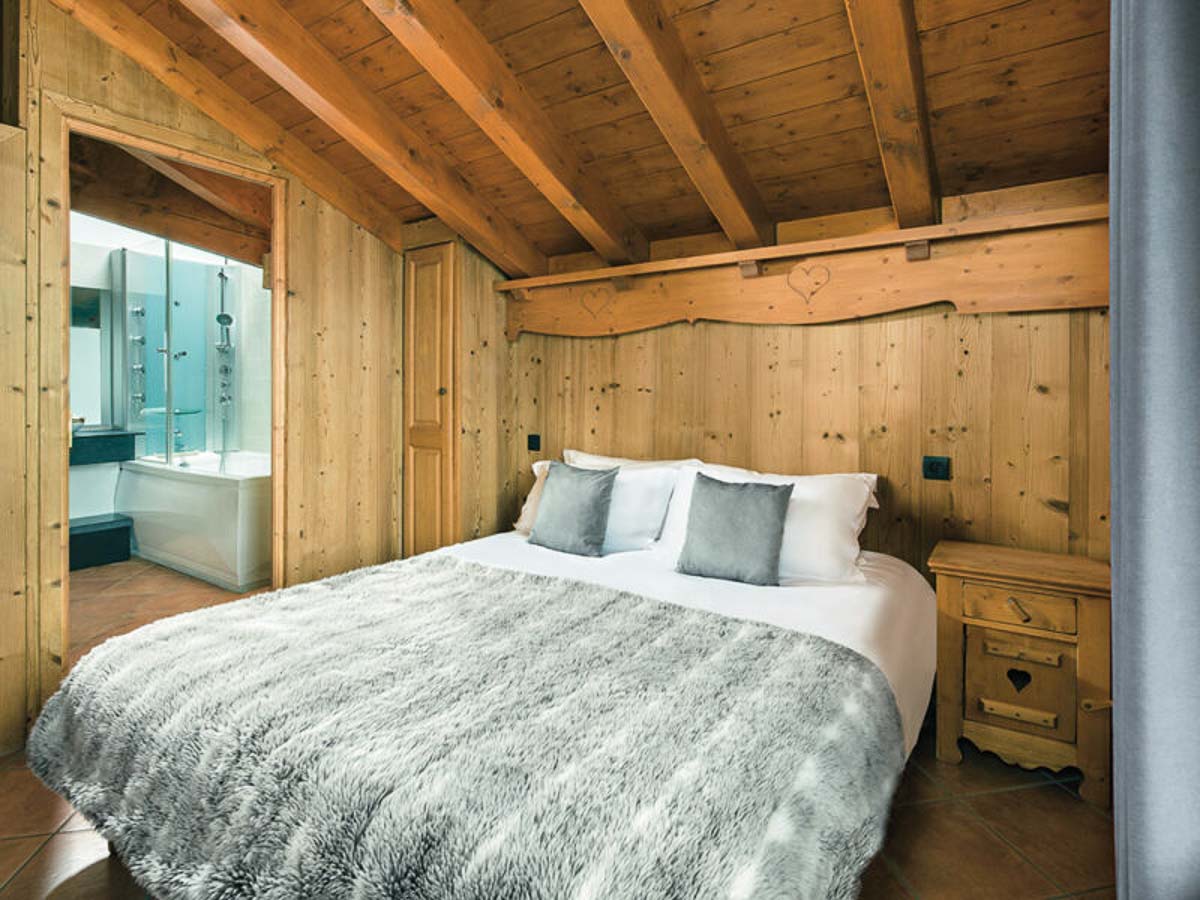 interior of hotel/chalet bedroom, wood clad and cosy looking with a fur bed throw, in a family friendly chalet in the 3 Valleys
