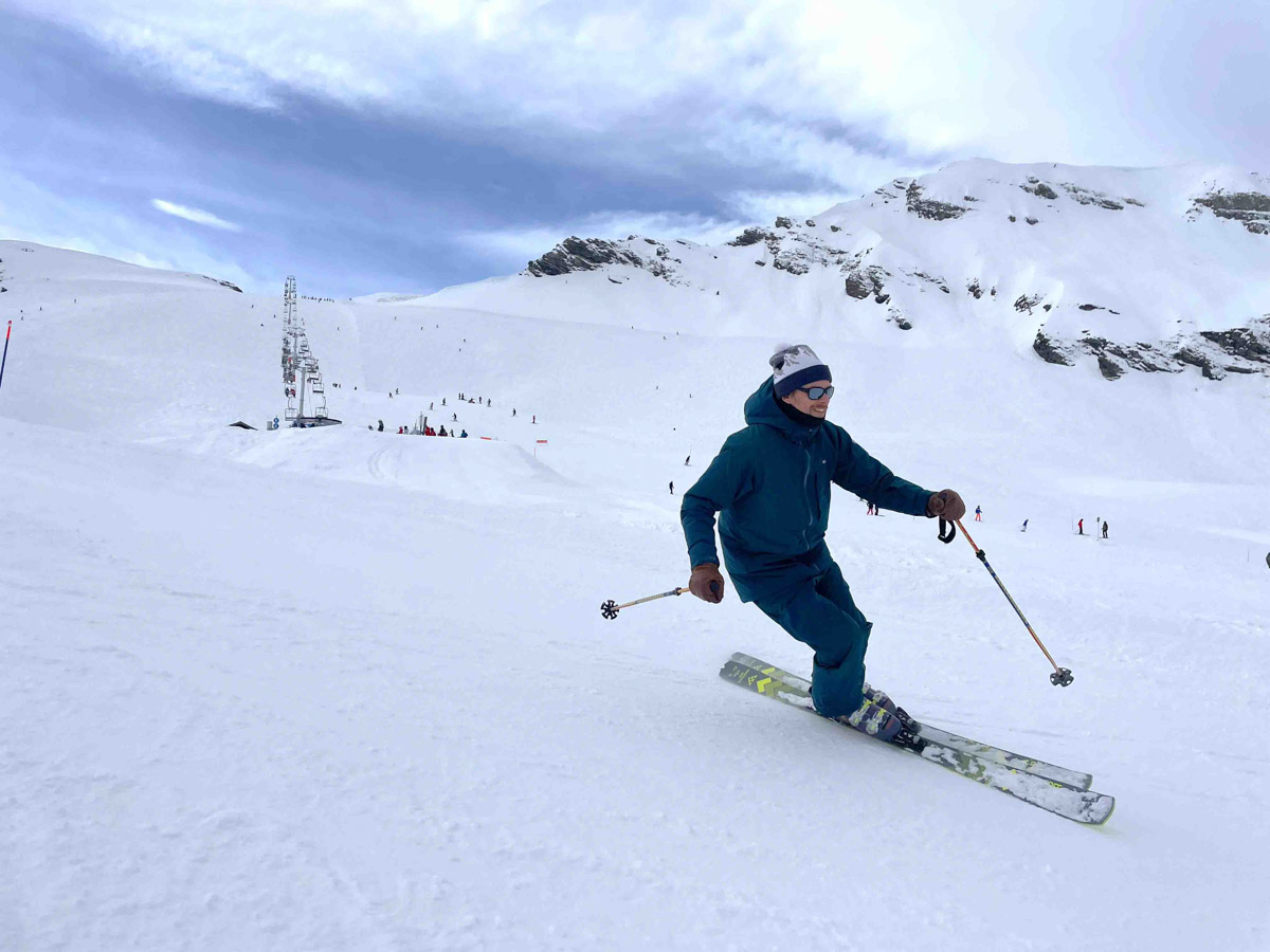 skier in slate green ski gear turns with ease down a mellow slope