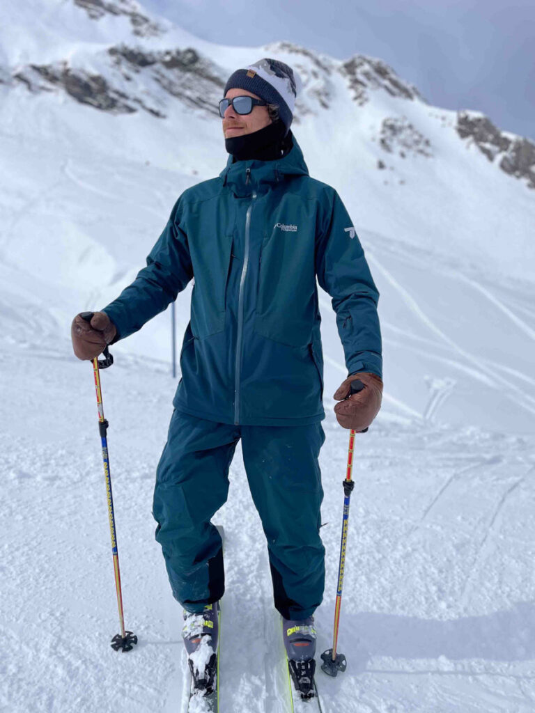 skier decked out in slate green poses on the mountain