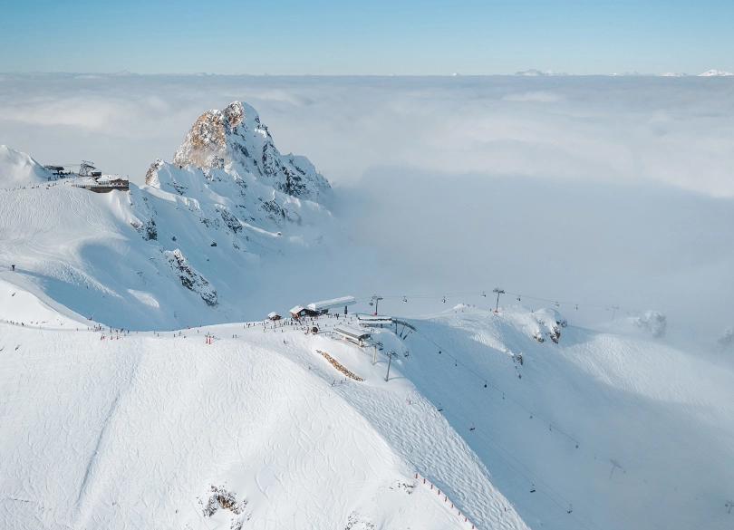 top station of ski resort shot from drone, the clouds below the peak