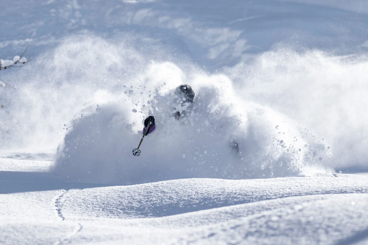 a skier lost in a coud of snow as they ski fresh pow