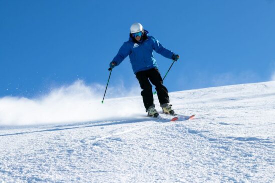 A ski instructor demonstrating relaxed parallel turns on a sunny slope, showcasing proper technique for smooth skiing.