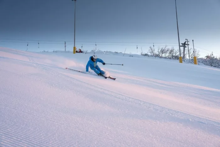 a skier on a corduroy piste, with a pastel light suggesting a Scandinavia location