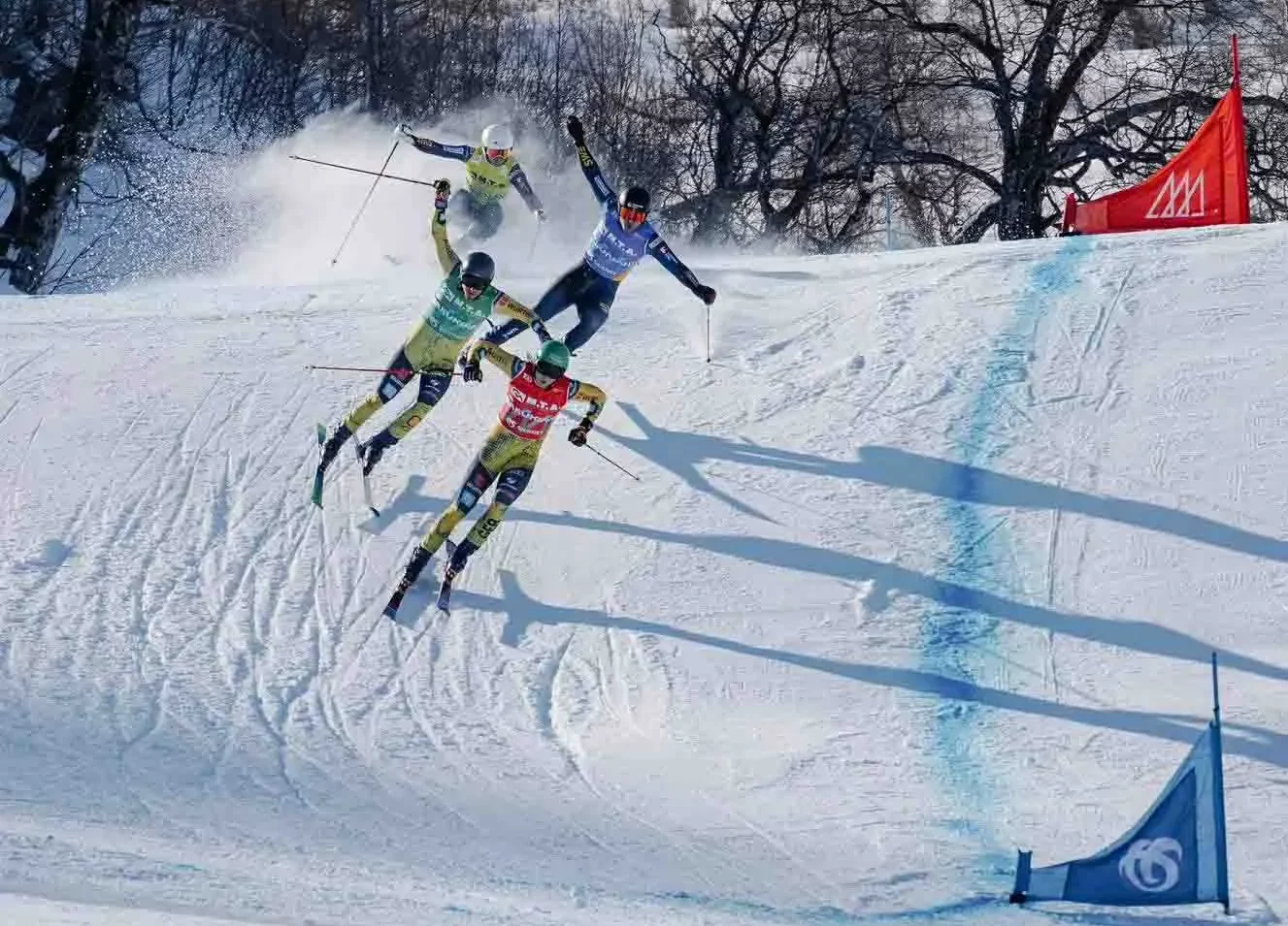 four ski-cross racers mid-air, on-course