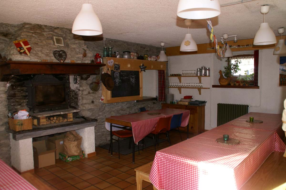 simple mountain refuge interior, with red check tablecloths and a huge fireplace