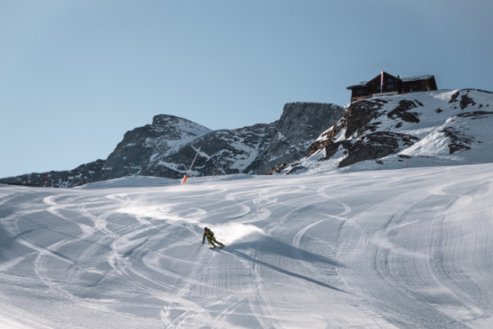 a skier on an empty piste, carving on a blue-sky day