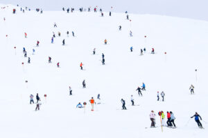 a white piste dotted with skiers