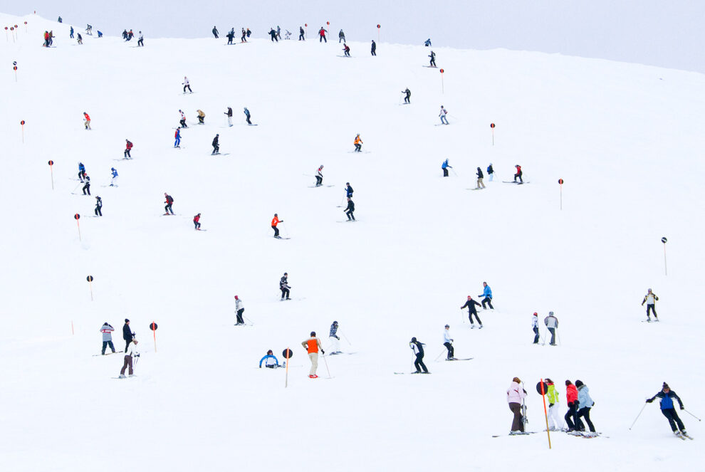 a white piste dotted with skiers