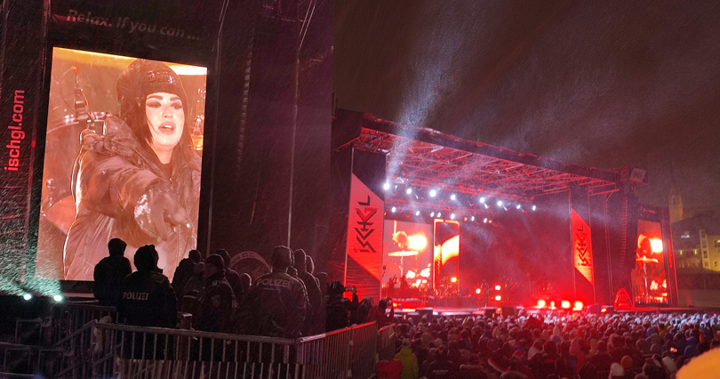 A festival/concert stage shines bright at night, Demi Lovato on screen