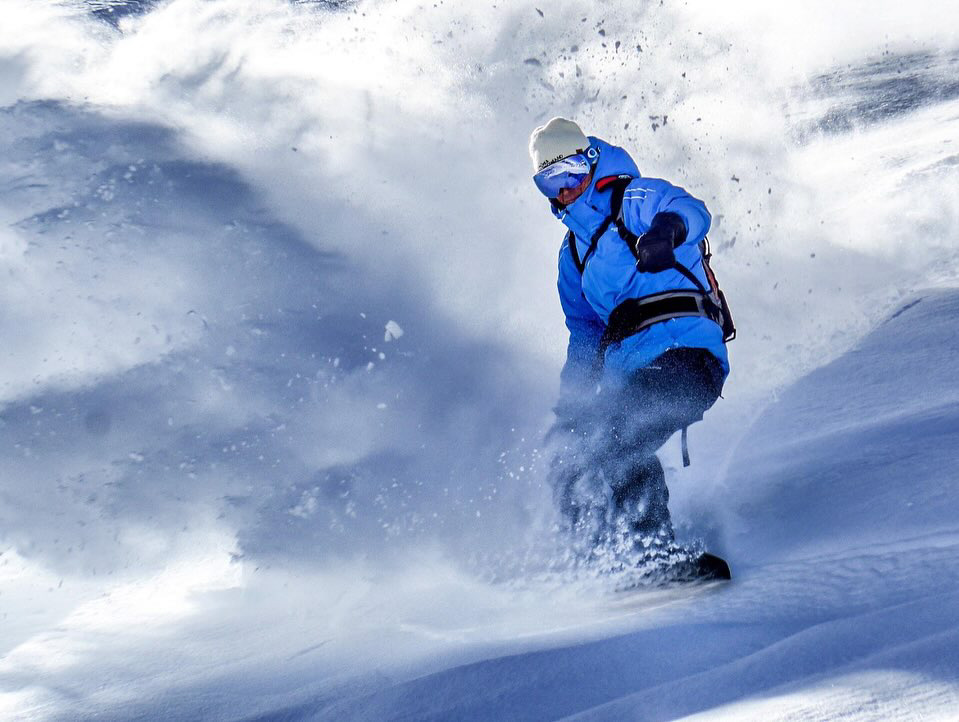 snowboarder exits from powdery snow cloud