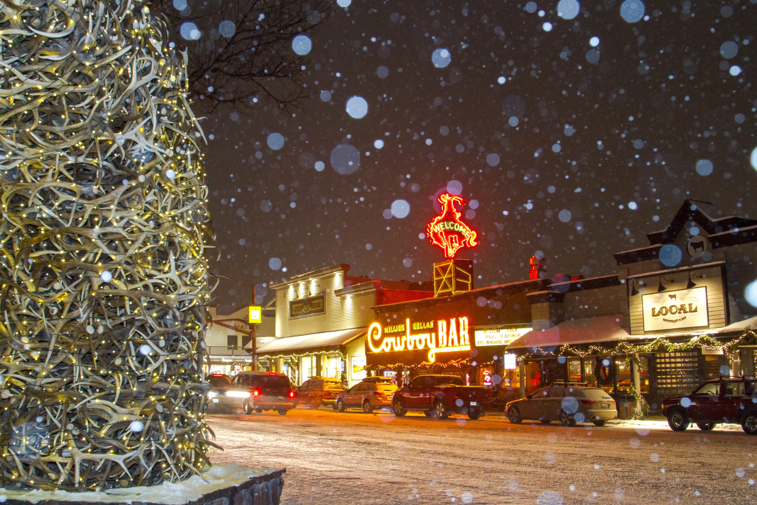 cowboy bar lit up at night, snow falling