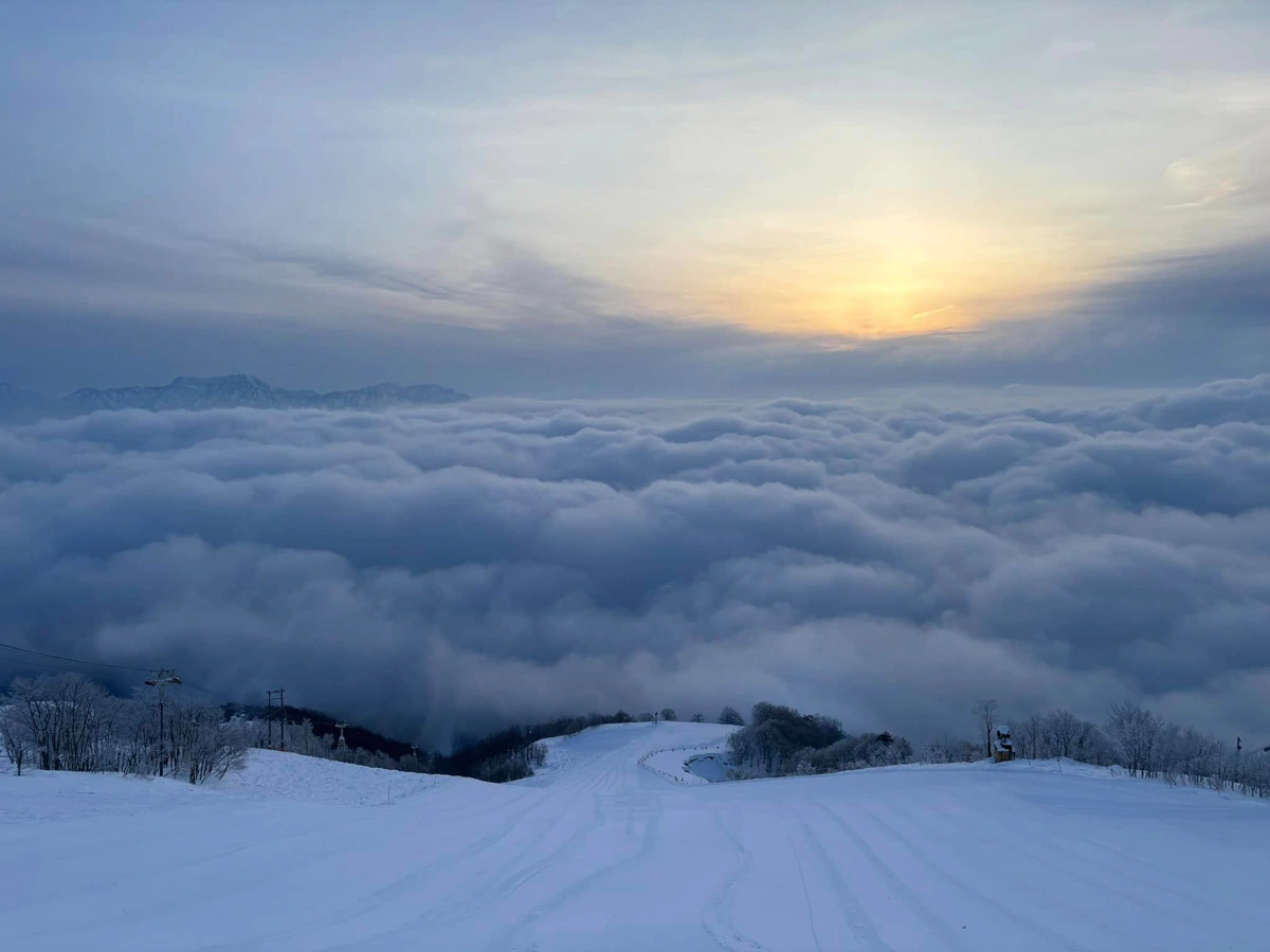 a sea of clouds at the end of an empty piste