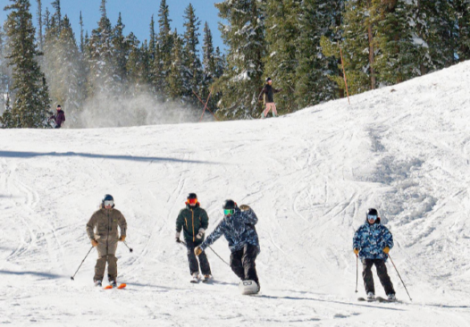 three skiers and a snowboarder on a ski slope