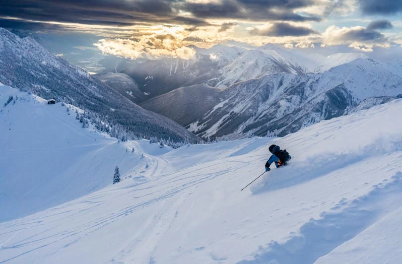 skier in deep pow, at sunset
