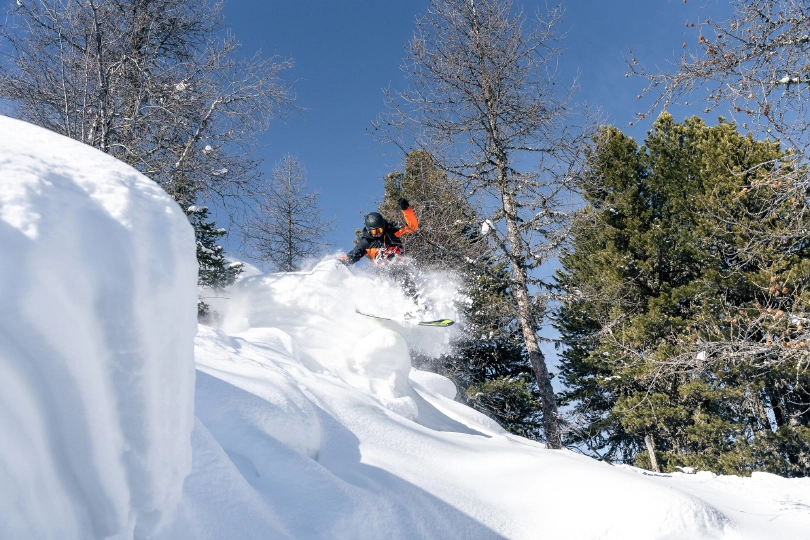 a skier pops off a lip in fresh powder
