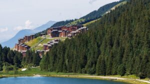 View of Méribel village above a forest and mountain lake in summer