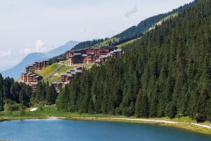 View of Méribel village above a forest and mountain lake in summer
