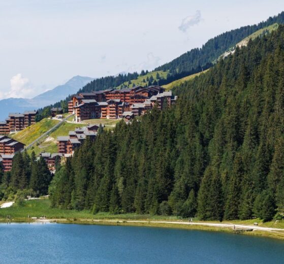 View of Méribel village above a forest and mountain lake in summer